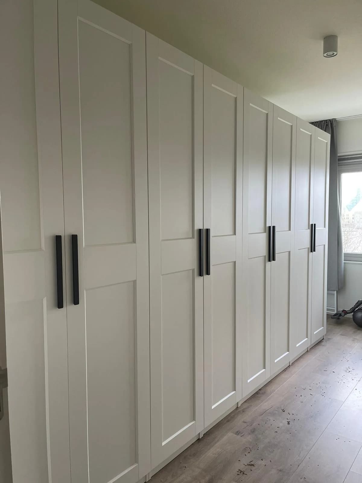 Frosted glass schuifdeur op een afgesteld IKEA PAX systeem in een licht Nederlands interieur