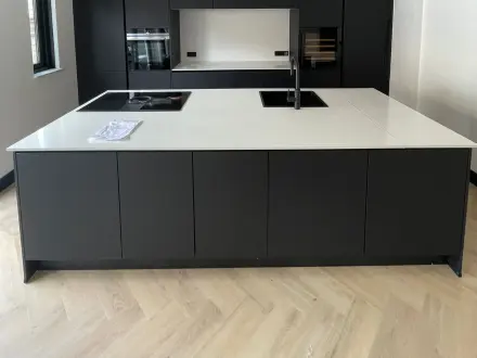 Afgemonteerde matzwarte keuken met wit werkblad, kookeiland met spoelbak en inbouwkookplaat